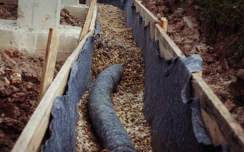 French drain installation beside foundation piers